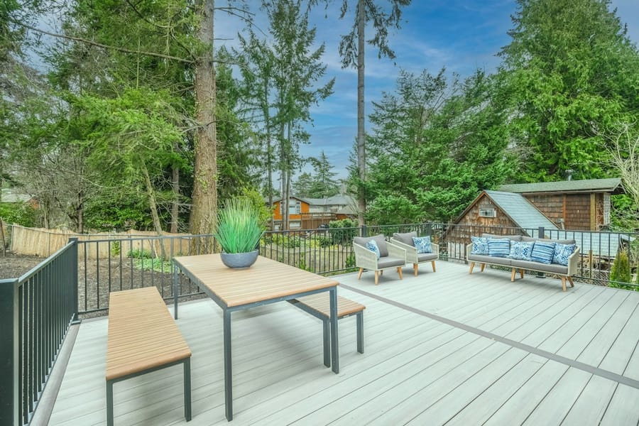 A clean backyard deck with a table, bench and outdoor sofas