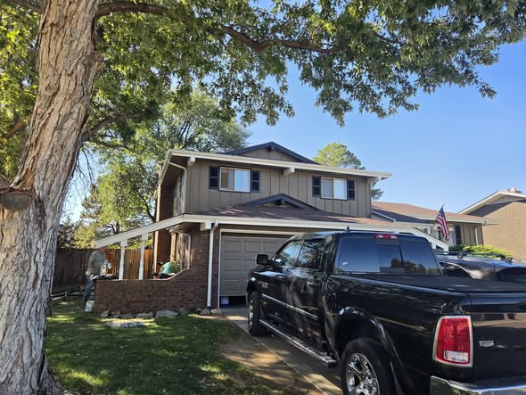 Two-story home with taupe board and batten siding, white gutters and trim, newly painted by Castro's Residential Painting